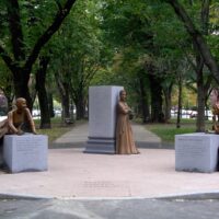 Sculptures of poets framed by tall trees