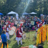 Sunbeams illuminate a crowd of colorfully dressed people.