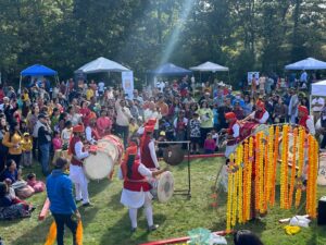 Sunbeams illuminate a crowd of colorfully dressed people.