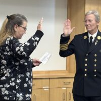 A town clerk and a uniformed fire chief with right hands raised as the new chief is sworn in.