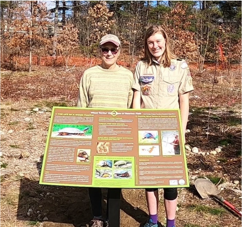 Two people hold a poster