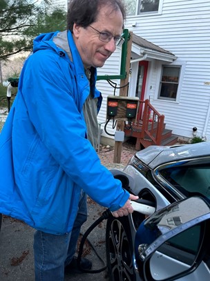 Man inserting charger into a Chevy Bolt. JuiceBox Level 2 chargers are in the background.