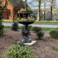 A Victorian-era cast zinc fountain planted with colorful flowers.