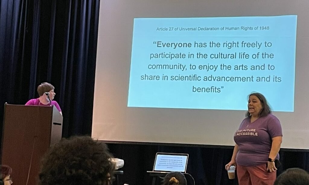 On stage - Anna Weinberger (left) and Executive Director Sam Gould; A slide on the screen shows Article 27 of the Universal Declaration of Human Rights