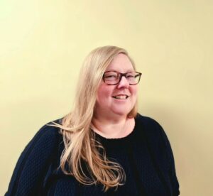 Woman with blond hair and glasses.