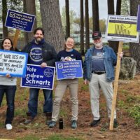 A group of 5 people smiling and holding political signs both for and against the override, Andrew Schwartz is also there, holding an Andrew Schwartz for School Committee sign.