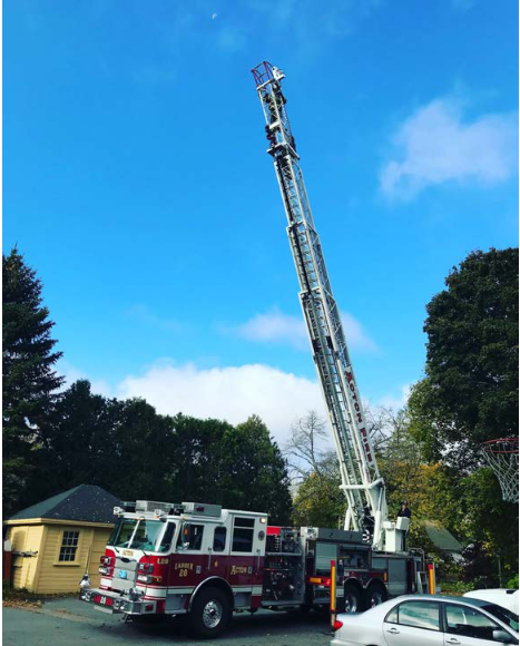 Acton's ladder truck with the ladder extended into the sky.