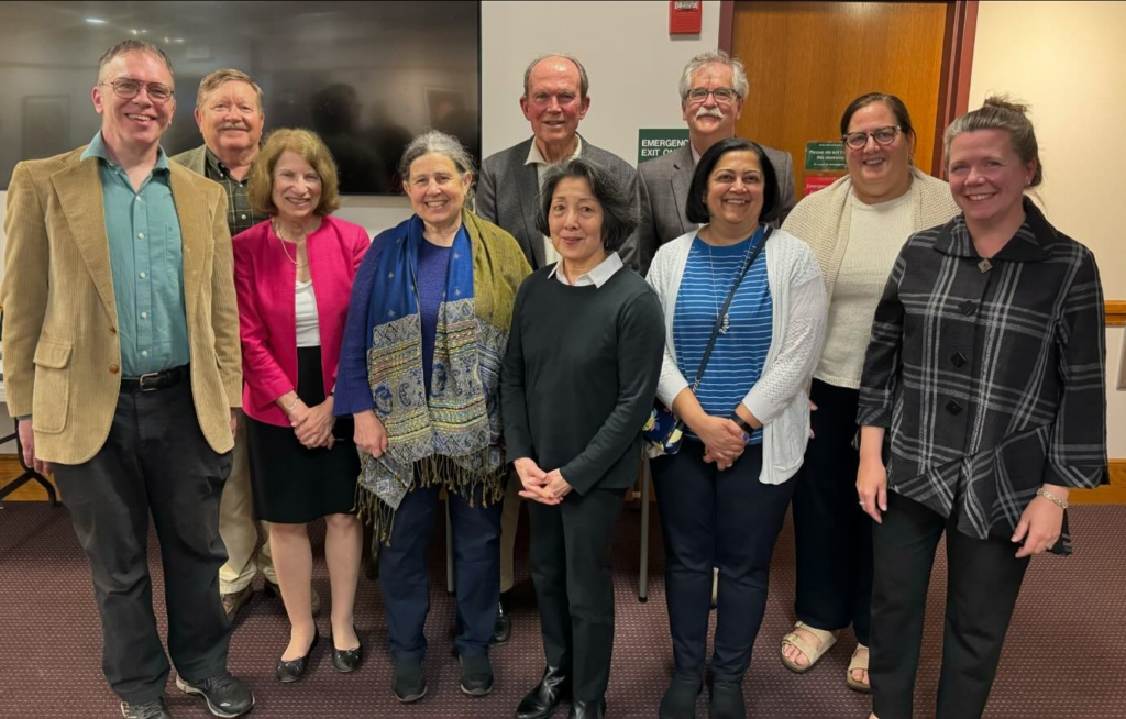 A group of people stand proudly in the Acton Memorial Library meeting room.