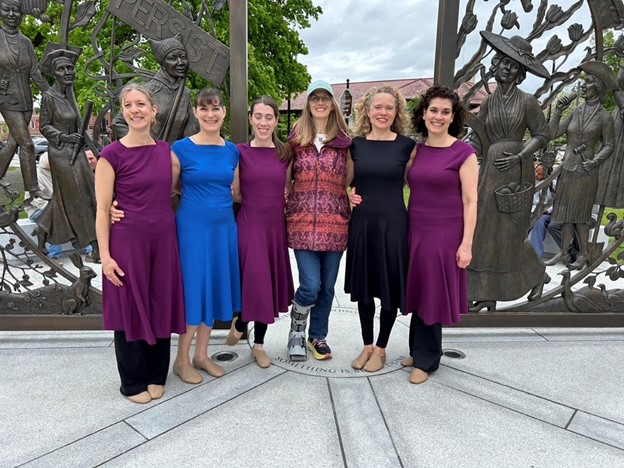 Six women standing in front of the sculpture. Five women are wearing dance tunics, and one, sadly, is wearing jeans and sporting an orthopedic boot.