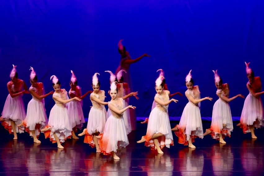 Photograph of 12 Asian dancers, in flowing white dresses with featured headpieces. 