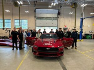 A front view of the Mustang with many people standing in the background.