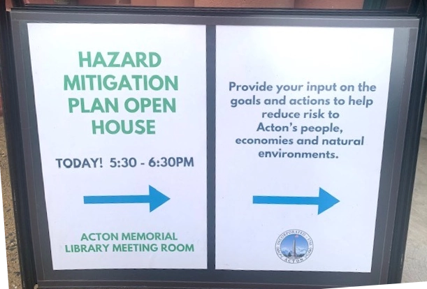 "Signs that point to the Hazard Mitigation Workshop at Acton Memorial Library meeting room. One sign has the time and location, the other sign says: Provide your input on the goals and actions to help reduce risk to Acton's people, economies, and natural environments The second sign includes the Town of Acton Seal."