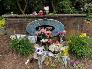 Many flowers, stuffed animals, and other items have been placed near the entrance to Christina's home at Pine Hill condominiums.