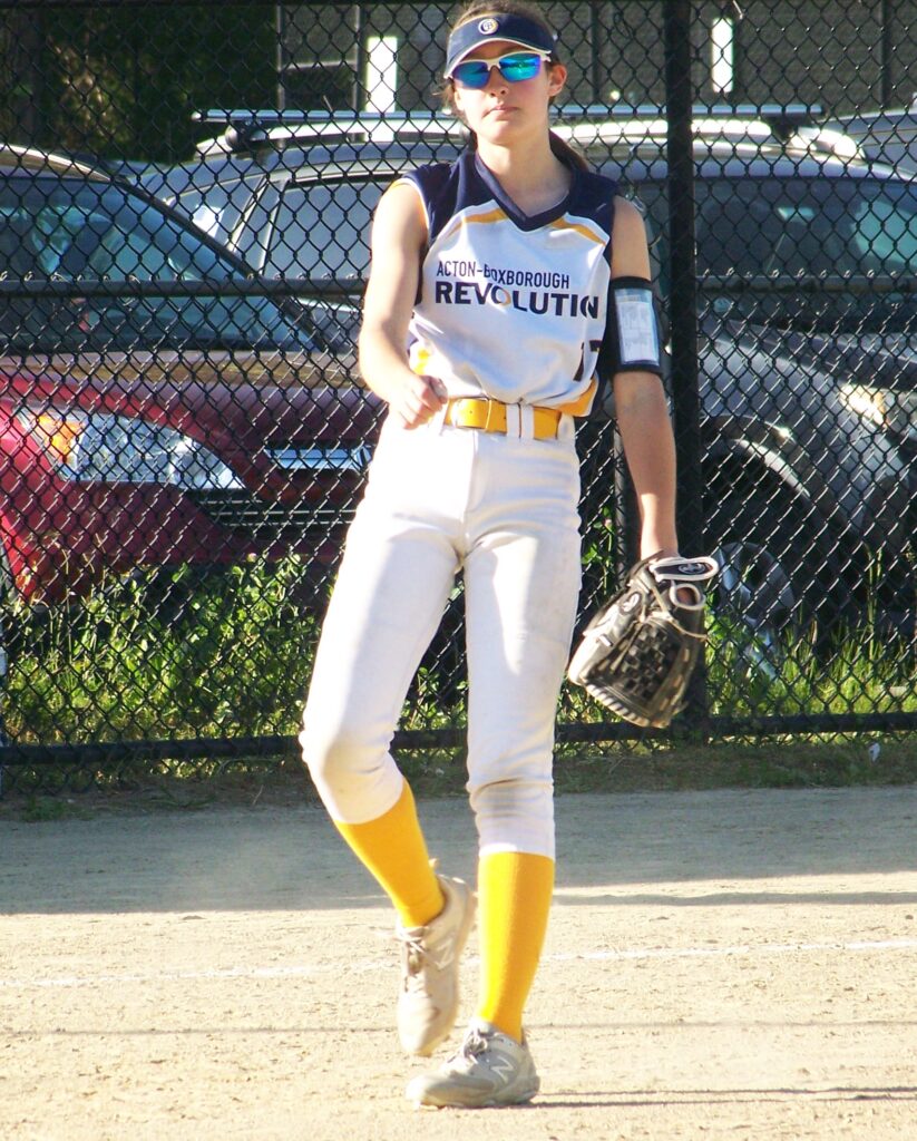 A young woman in a Revs uniform watches the field.