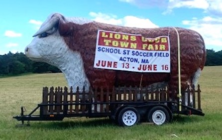 A giant brown and white cow appears every year on the School Street field to announce the Lion's Cllub Fair. It is in a trailer and sports a sign on its side that announces that the Lion's Clube Town Fair will be held on the School Street Soccer Field, June 13 - 16.