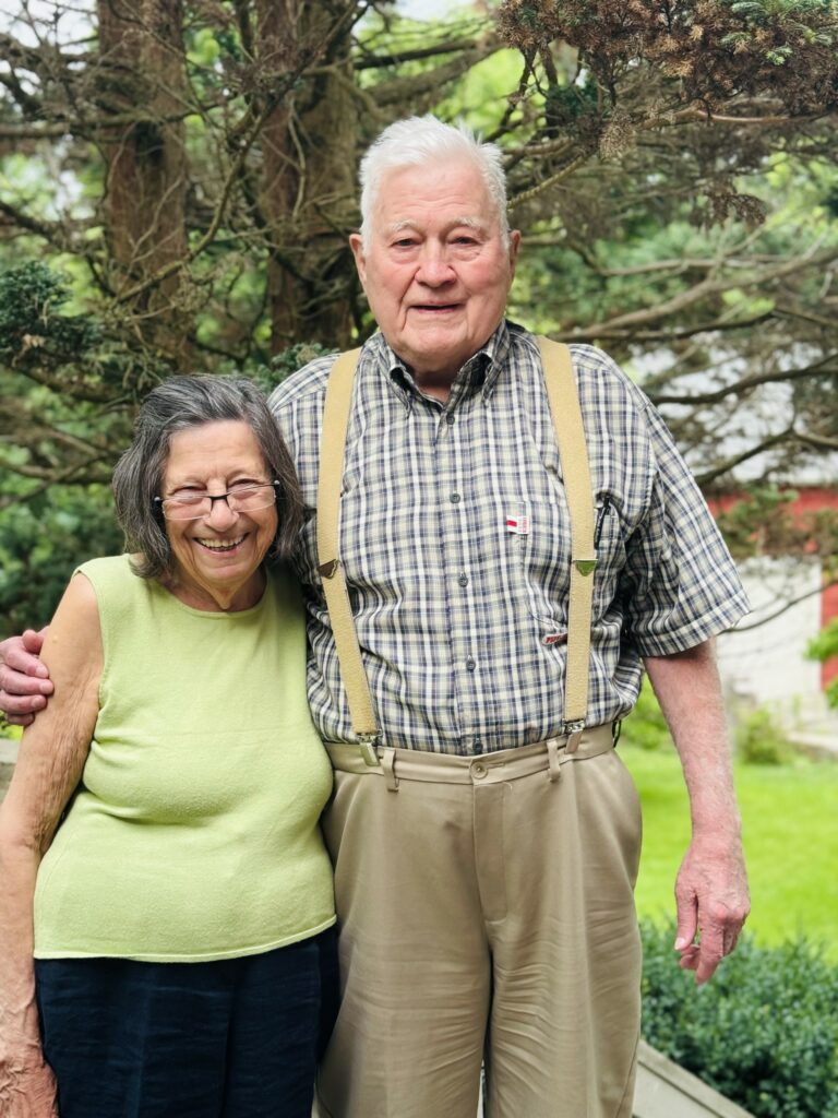 Another picture of the same couple. They are standing outside, in front of some trees, and the woman looks like she's about to break into giggles.