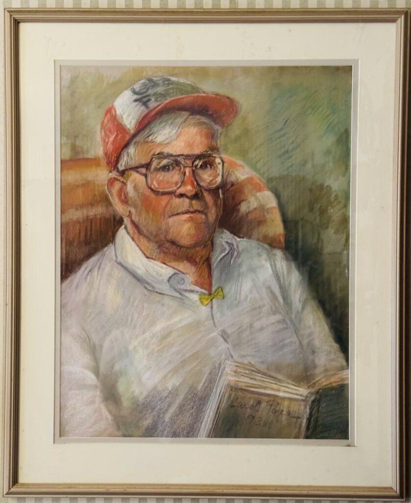 An oil painting of a seated man wearing a baseball cap and a white button-down shirt. He is reading a book and has a teeny tiny yellow bow clipped to his open-necked shirt.