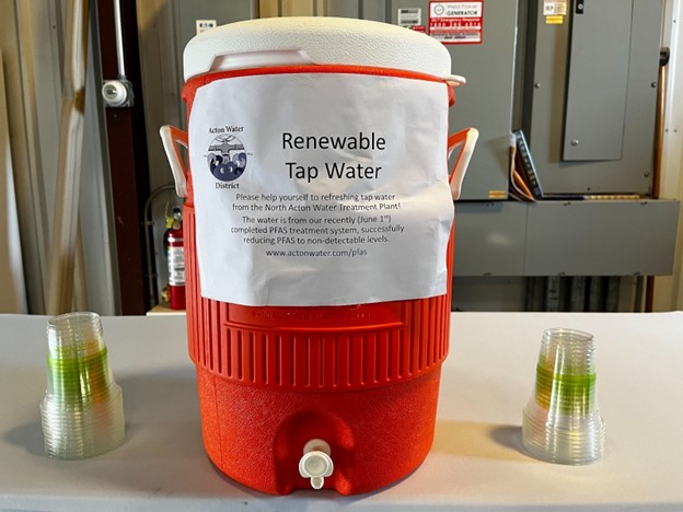 A large water jug sits on a table next to some (recyclable) plastic cups. A sign on the jug states that it contains Renewable Tap Water. The sign continues: Please help yourself to refreshing tap water from the North Acton Water Treatment Plant! The water is from our recently (June 1st) completed PFAS treatment system, successfully reducing PFAS to non-detectable levels. www.actonwater.com/pfas