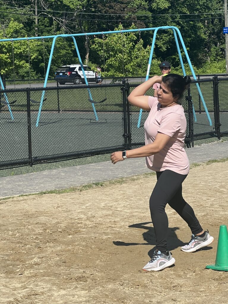 A woman has her arm back, ready to throw a cricket ball.