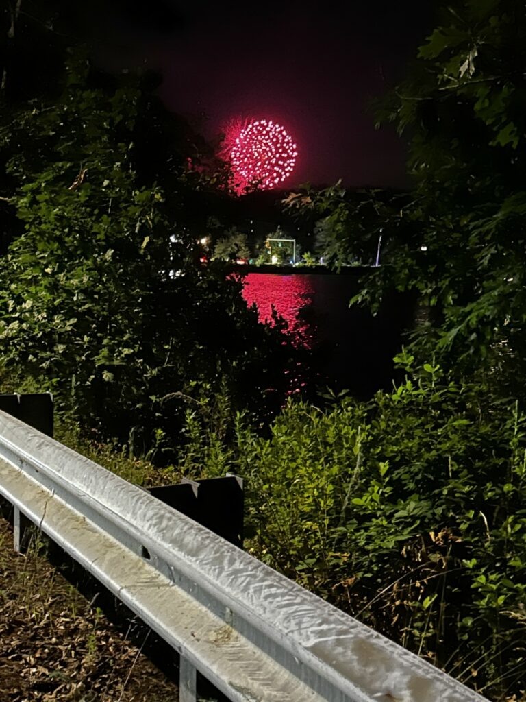 Fireworks in the sky are reflected on Nagog Pond.