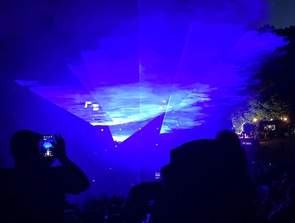 A laser show lights up the night sky with blue lights. With a little imagination, it could look like a UFO.