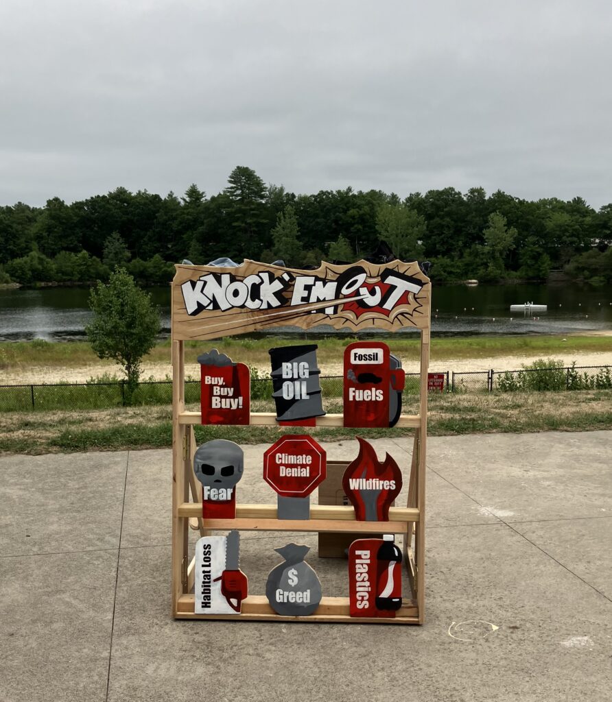 A large wooden game -- Throw a bean bag to knock out items such as Climate Denial,Greed, Big Oil, and Wildfires.