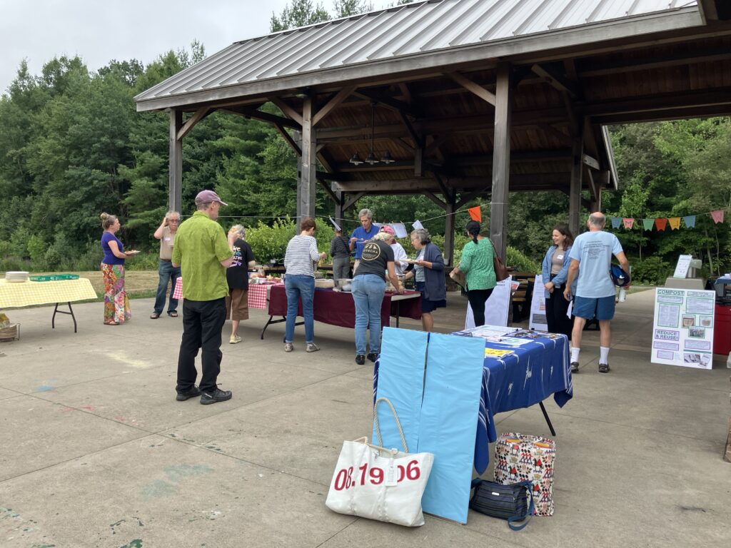 People surround a table to get food. In the foreground, there's a table with information from Energize Acton.