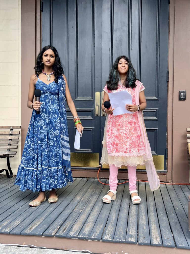 Two young women wearing Indian clothing stand in the Town Hall portico.