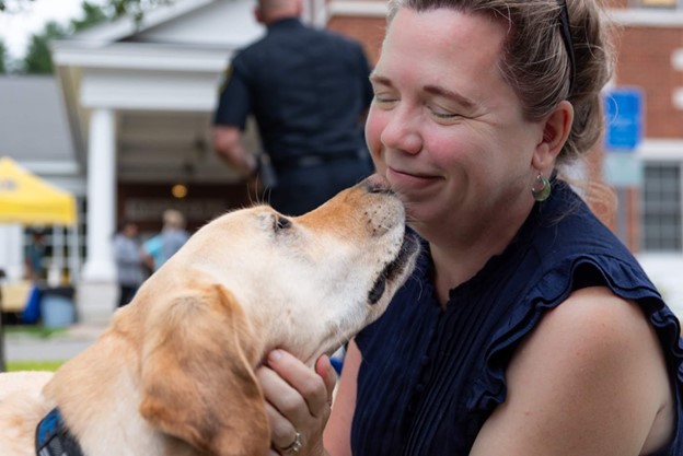 A golden retriever licks the face of a smiling woman.