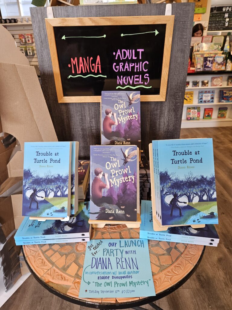 A display of books featuring "The Owl Prowl Mystery" and "Trouble at Turtle Pond," both by Diana Renn. There is also a hand-written sign that says " Get excited for our Launch Party with Diana Renn (The Owl Prowl Mystery) in conversaion with local author Elaine Dimopoulos. Tuesday, September 10th @ 7PM.