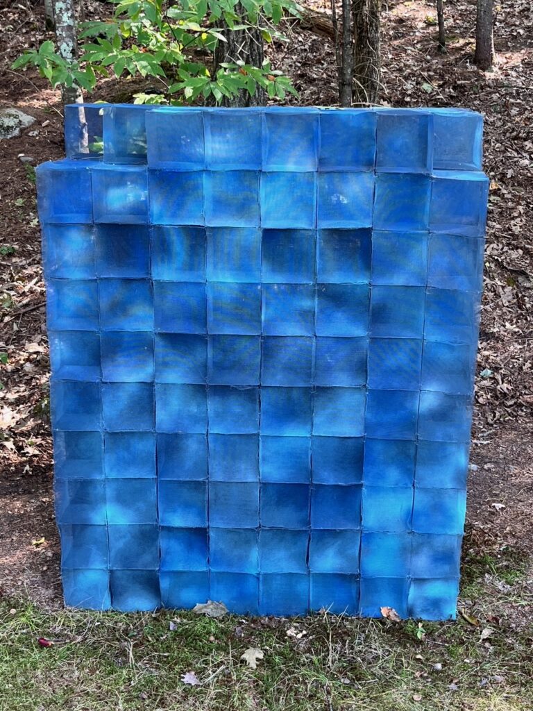 A large blue almost completed cube that is made up of smaller canvas cubes.