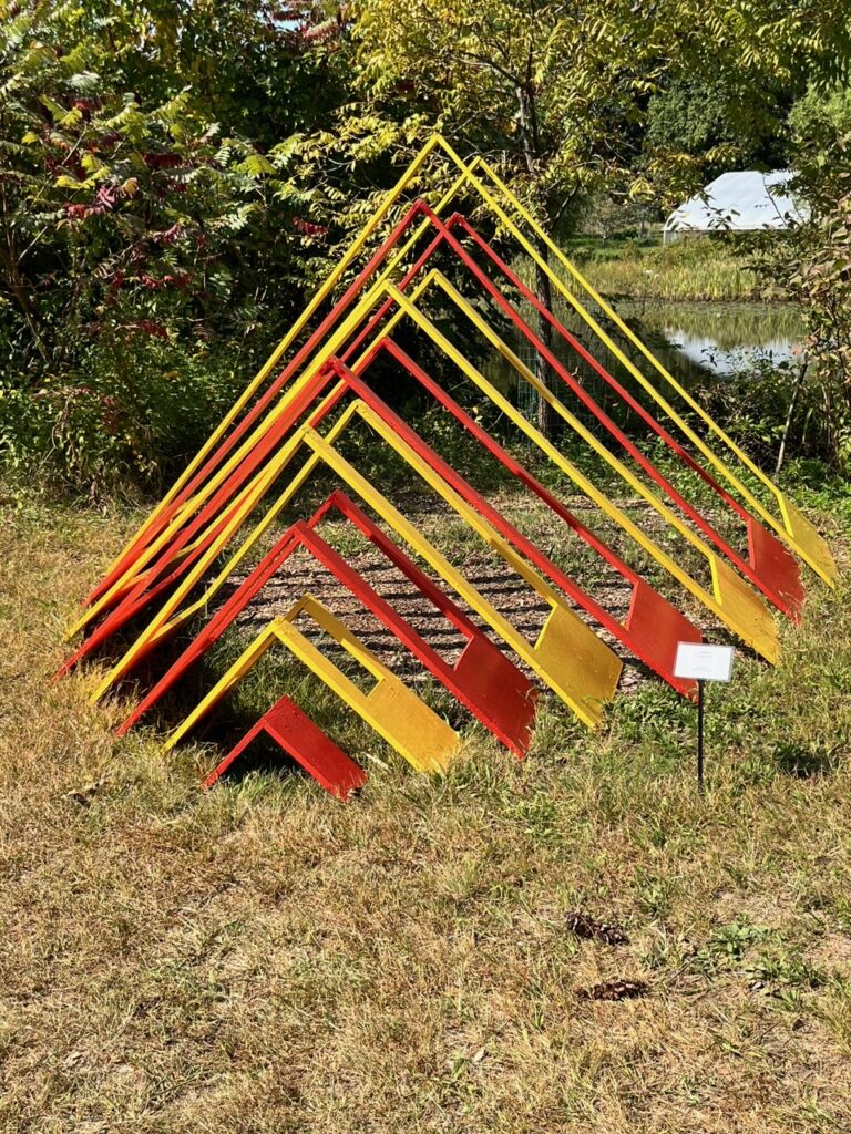 Metal triangles of increasing sizes (from about 8 inches to 3 1/2 feet tall). The triangles are in alternating yellow and red, mimicking the colors of the sunset.