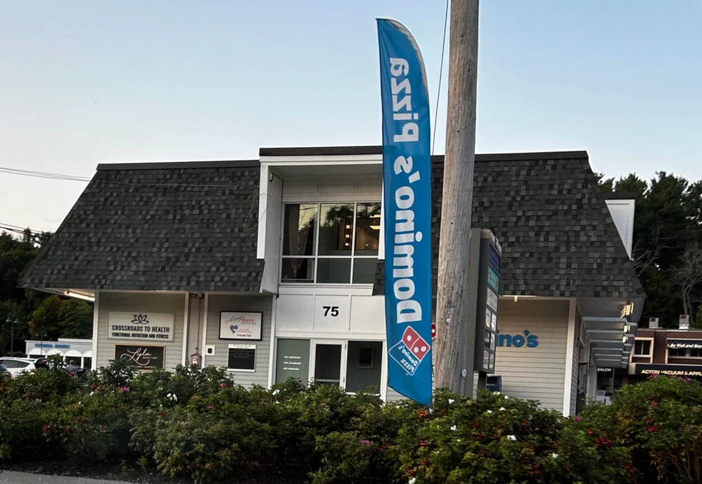 Modern building with large slanting slate grey roof and plate glass windows, with a backward Domino's Pizza banner hanging in front.