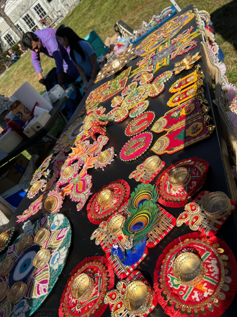 A table full of indian crafts, brasswork, peacock feathers, and fabric.