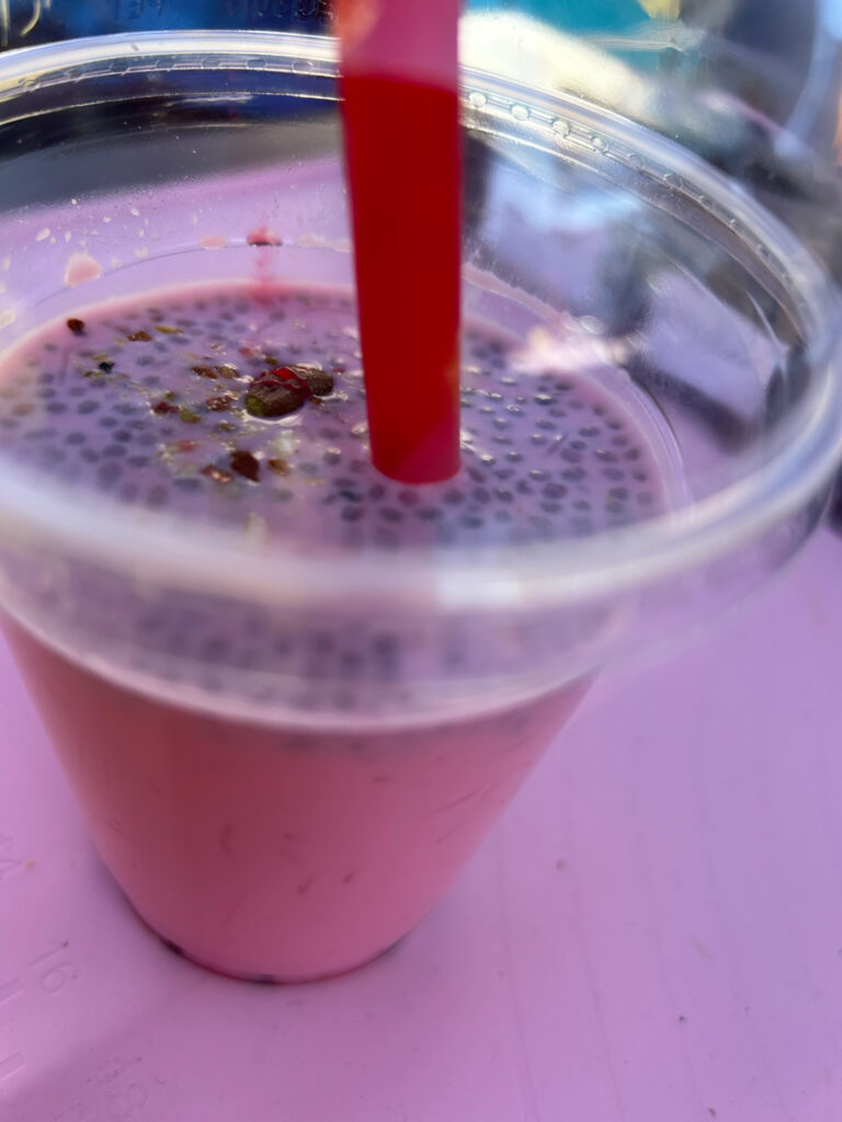 A very pink drink with some kind of dots on top (tapioca pearls, maybe?).