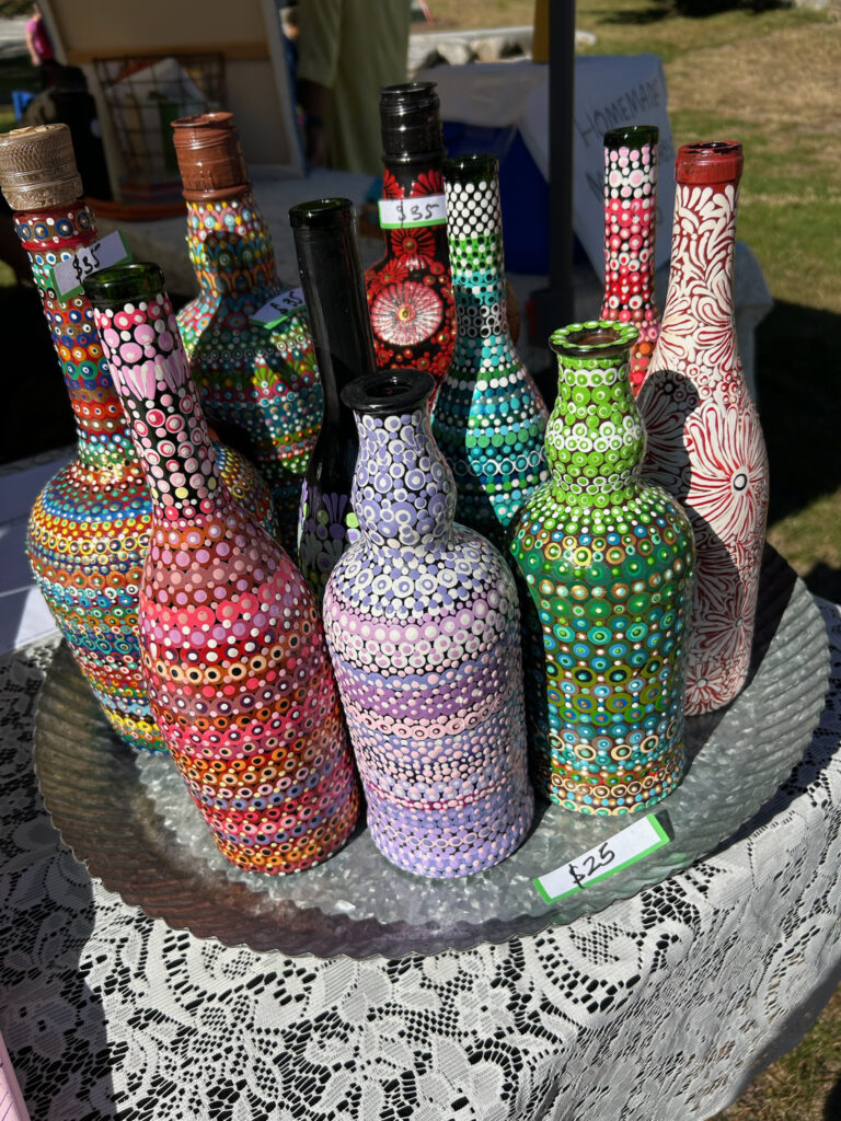 A table full of bottles that are painted with colorful dots or flowers.