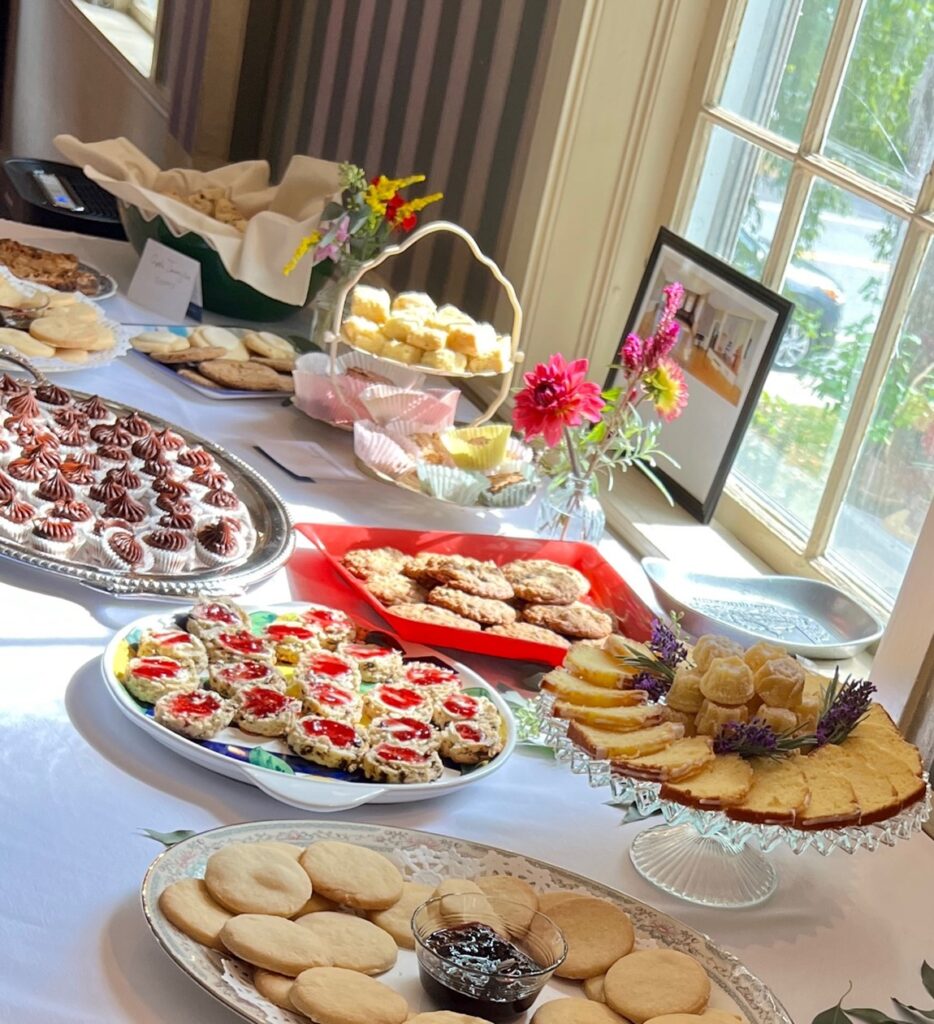 A table set with a white tablecloth and many plates with sweets.