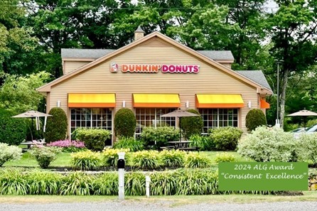 A nicely laid out formal garden with tall grasses and shrubs. The Dunkin' Donuts building is in the background.