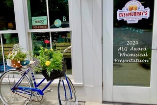 Eve and Murray's door with a blue bicycle parked next to it. The bike has two flower baskets (both front and back) that are always filled with seasonal flowers.