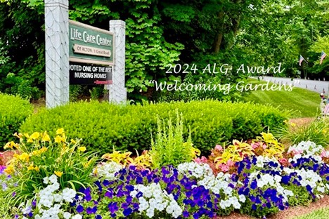 A flower garden in front of the Life Care Center sign. In the front there are flowers of many colors.