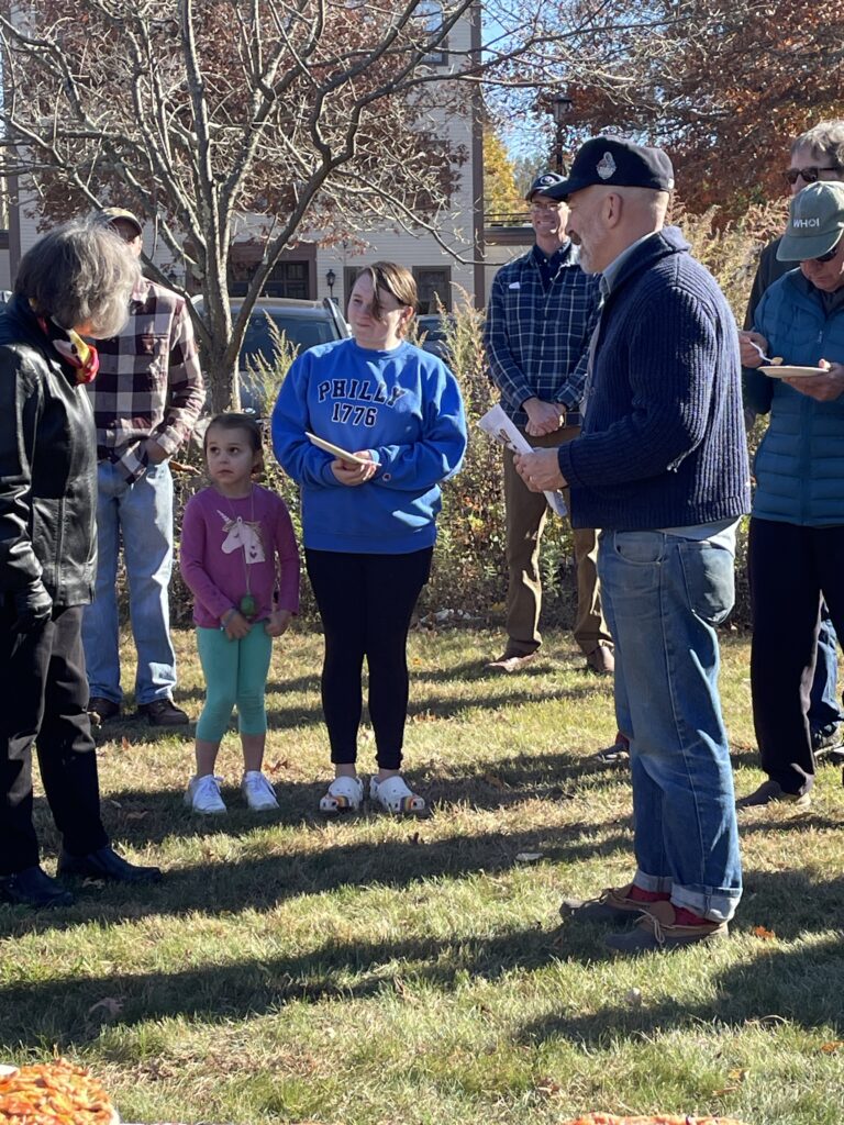 A teen in a blue Philly 1776 sweatshirt chats with two adults.