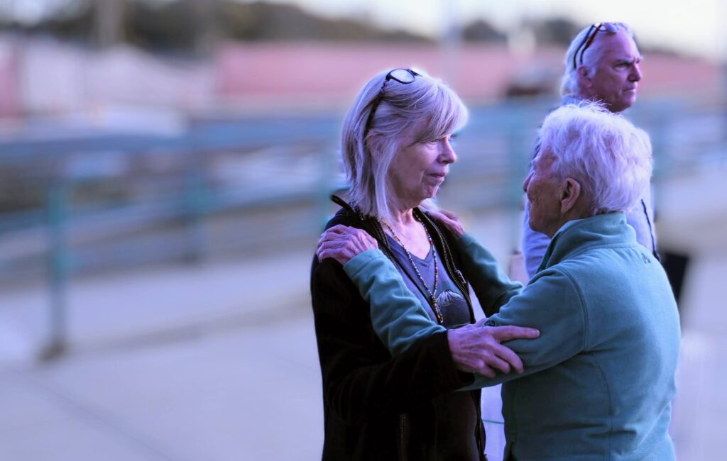 Two women -- one (Marian Stoddart) has her hands on the shoulders of the other (Susan Edwards). Ms Edwards hass her hand on Ms Stoddarts upper arm.