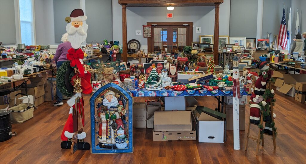 Inside of a hall, tables crammed full of stuff await.