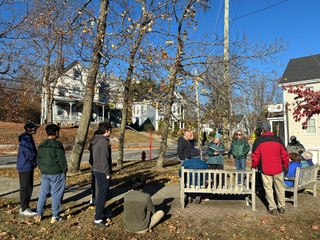 A group of people standing by some park benches on School Street.