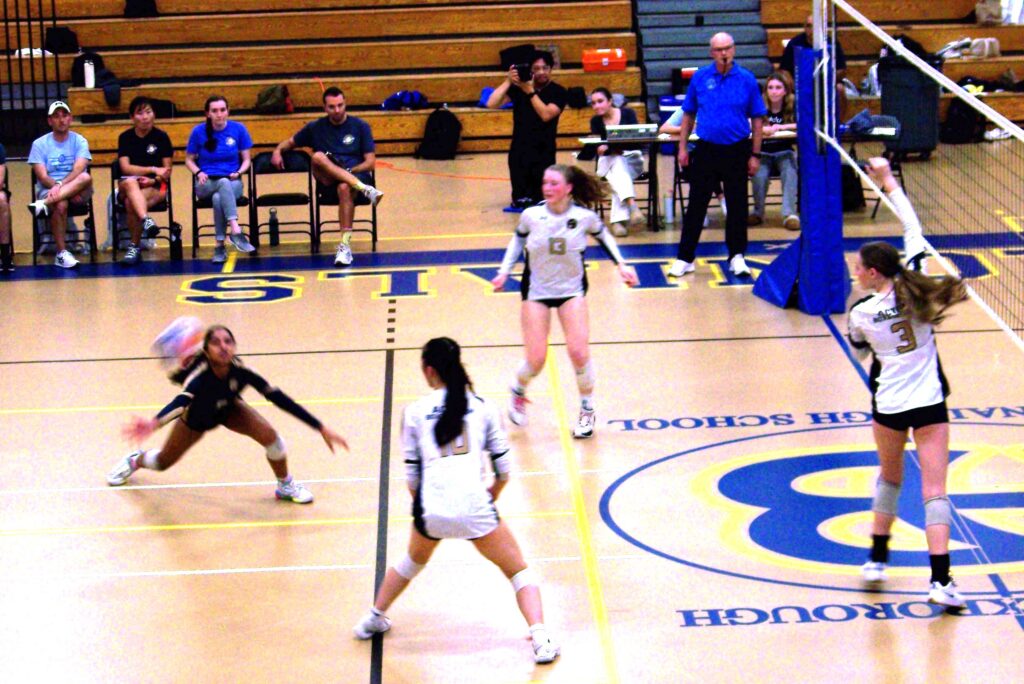 A young woman gets ready to dig for an incoming ball.