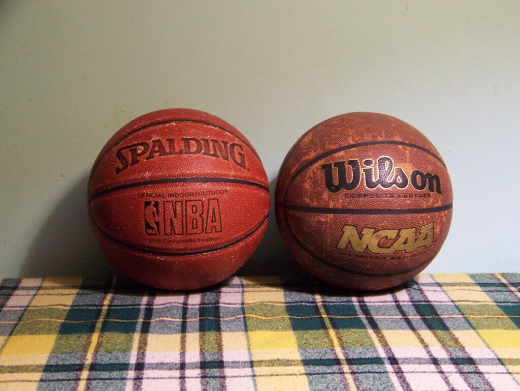 Two older basketballs on a plaid blanket.