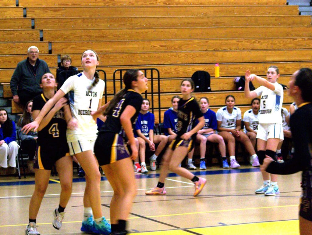 A group of girls in a gym seem to be looking towards and incoming ball.