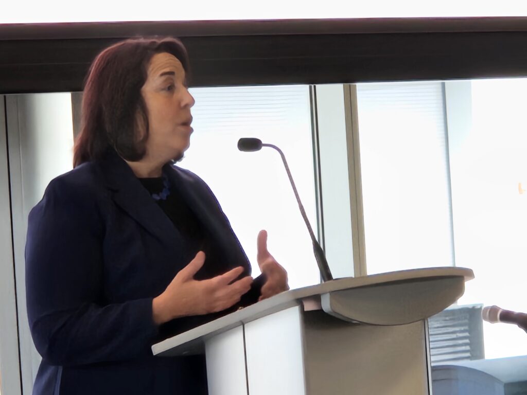 A woman speaks from a podium.