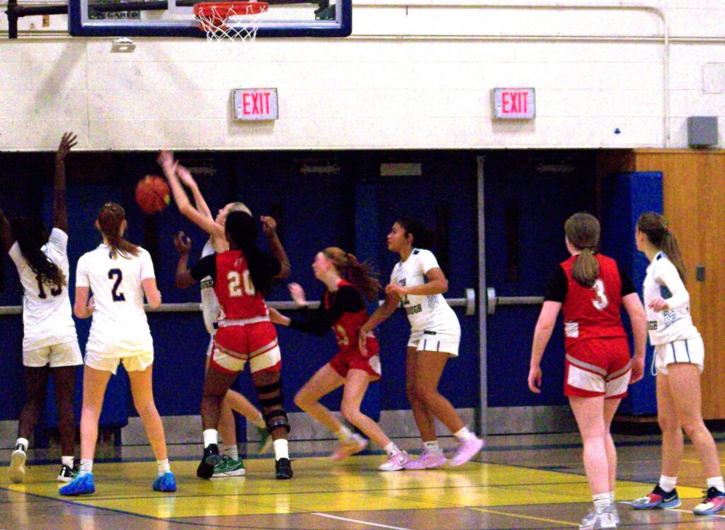 A group of girls head towards the basketball.