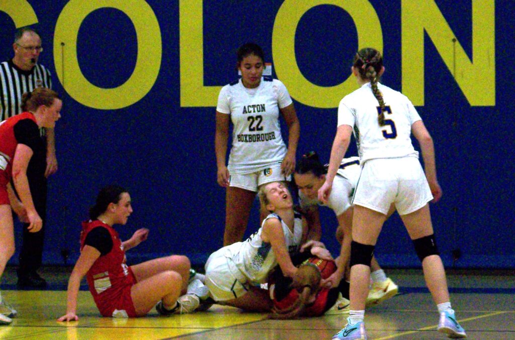 Two Waltham players and an AB player are on the ground. The ref is heading over and other girls stand by.